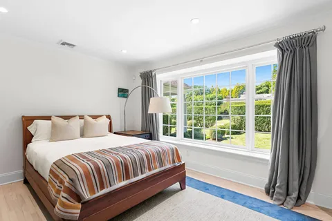 a bedroom with a bed lamp and a large window with outer view