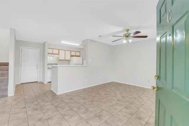 an empty room with a bathroom and a chandelier fan
