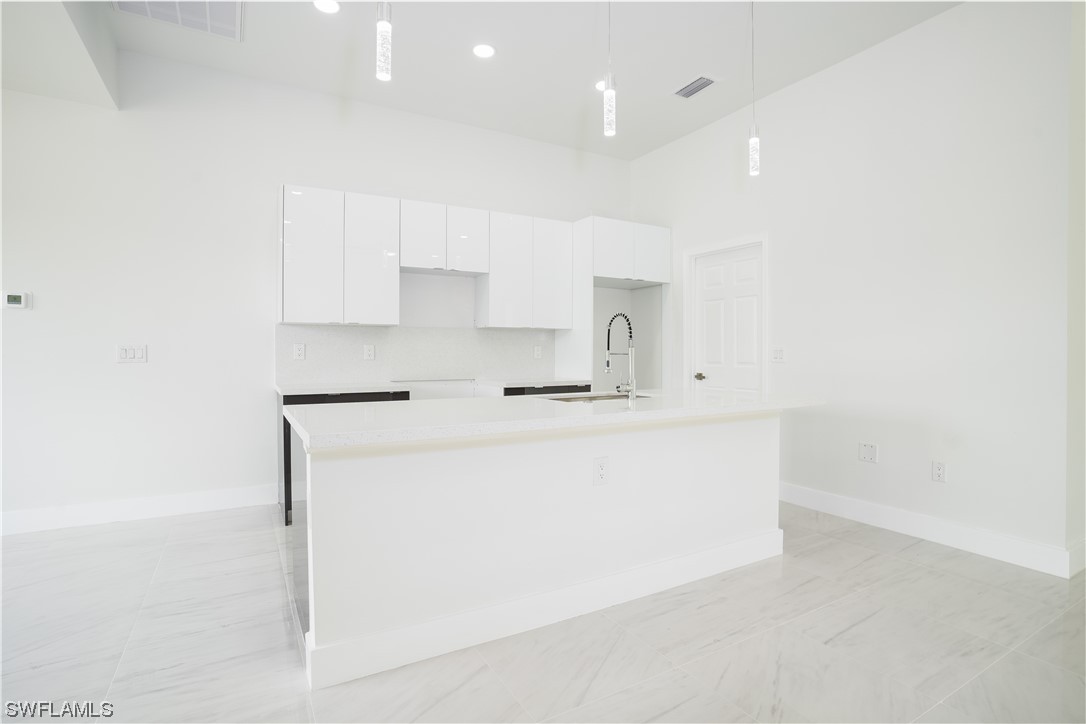 3233 Ruth Lane Lehigh Acres, FL 33976 - Photo 7 of 23 a kitchen with kitchen island a sink a stove a refrigerator and white cabinets