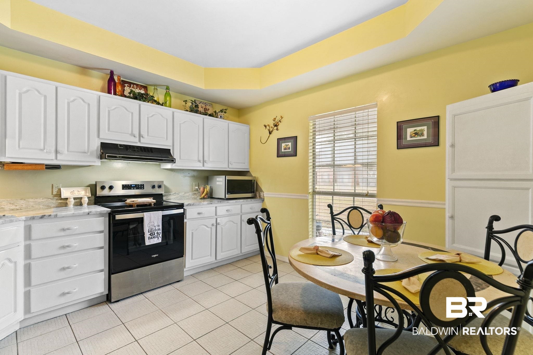 519 Juniper Place Drive Foley, AL 36535 - Photo 14 of 47 Kitchen with a raised ceiling, stainless steel appliances, white cabinetry, under cabinet range hood, and light tile patterned flooring