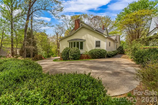 a view of a house with a yard and large trees