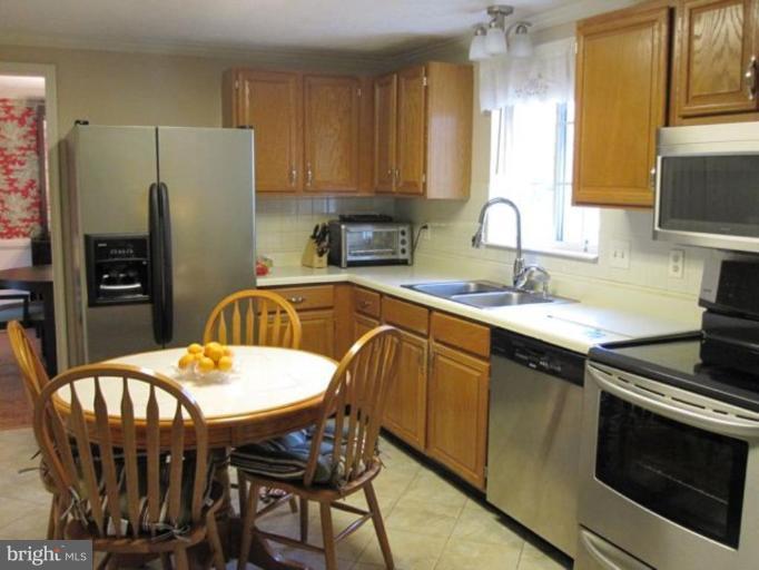 4438 Cub Run Road Chantilly, VA 20151 - Photo 3 of 16 a kitchen with stainless steel appliances granite countertop a sink a stove a dining table and chairs