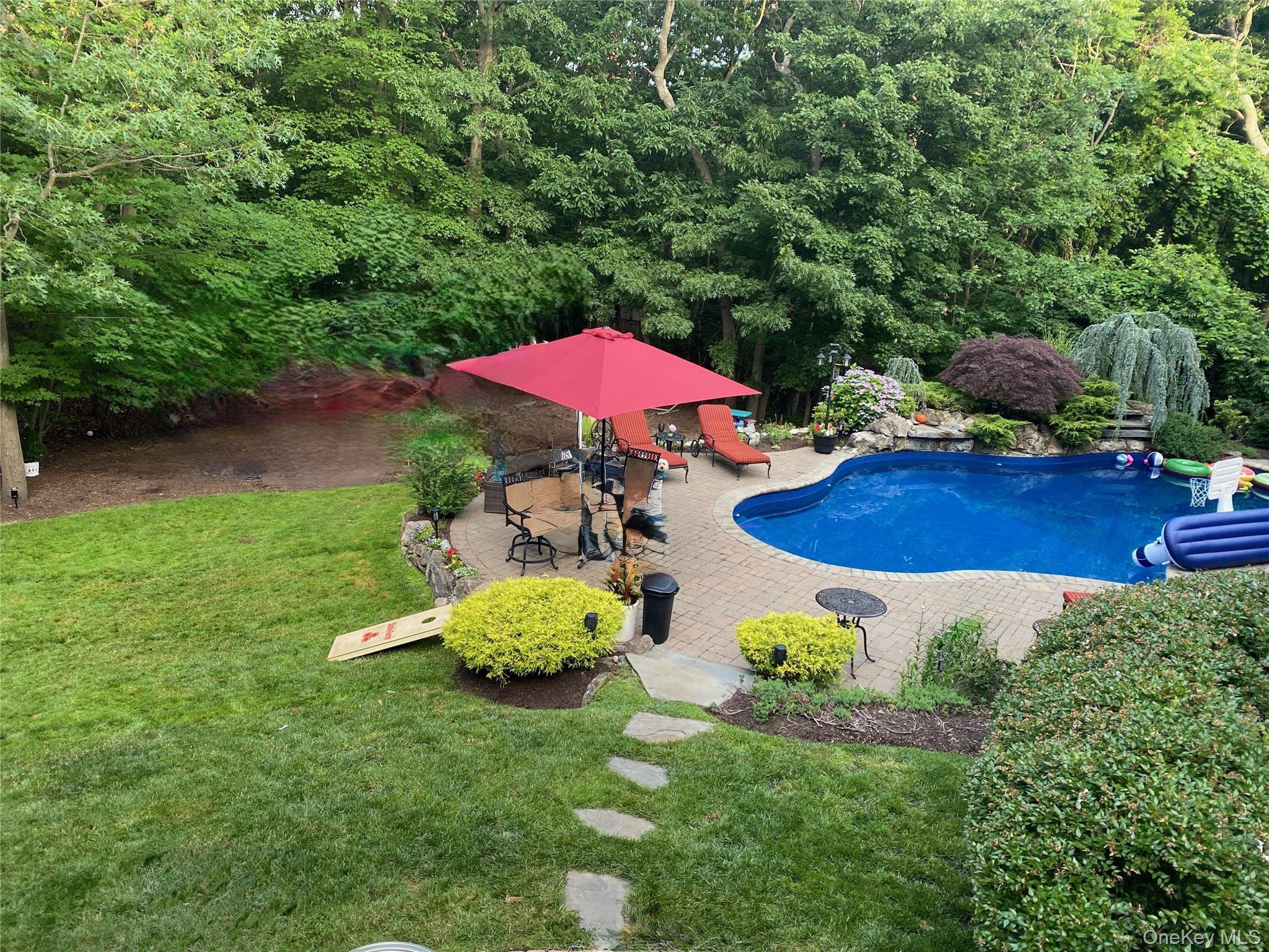 5 Frost Valley Road Mount Sinai, NY 11766 - Photo 37 of 49 a view of a swimming pool with lawn chairs under an umbrella