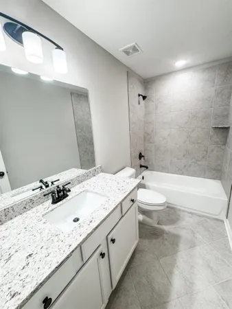 a bathroom with a granite countertop sink mirror toilet and bathtub