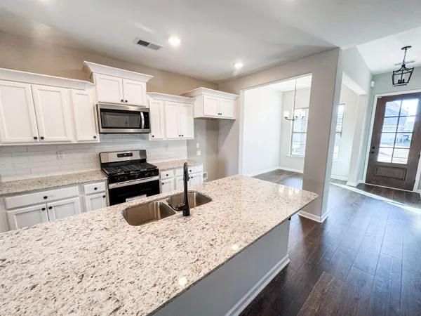 a kitchen with stainless steel appliances kitchen island granite countertop a stove a sink and a microwave