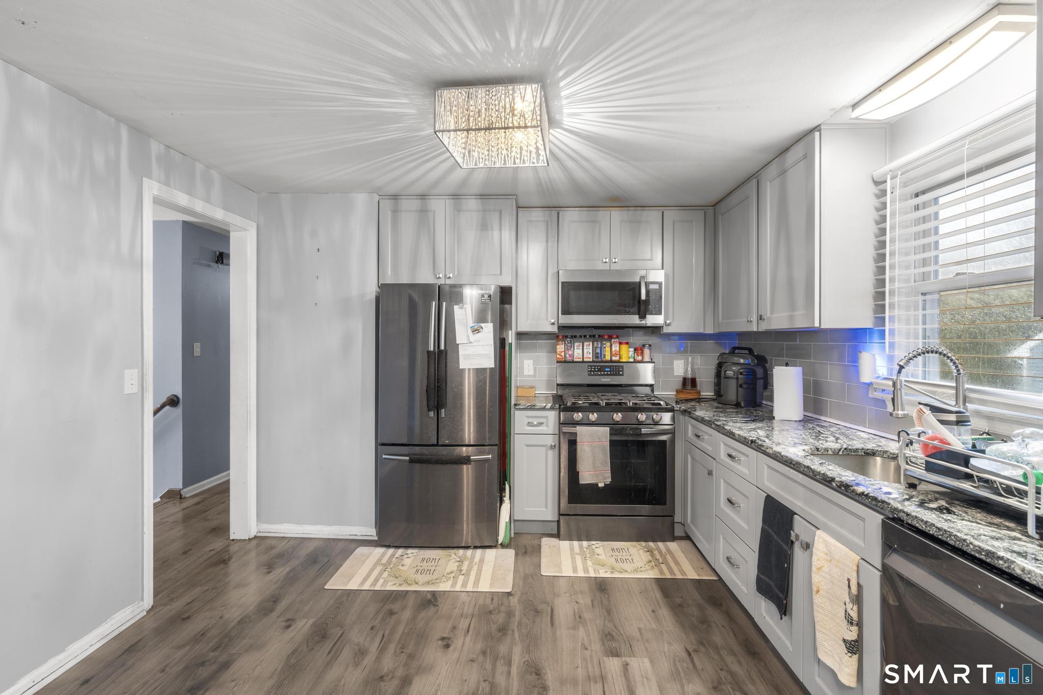 7 Pettit Drive Meriden, CT 06451 - Photo 12 of 35 a kitchen with kitchen island granite countertop a refrigerator a sink dishwasher a stove top oven a refrigerator with grey cabinets and wooden floor