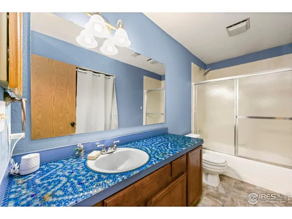 a bathroom with a granite countertop sink a toilet a mirror and shower