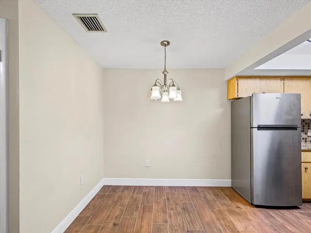 a view of a room with wooden floor and a refrigerator