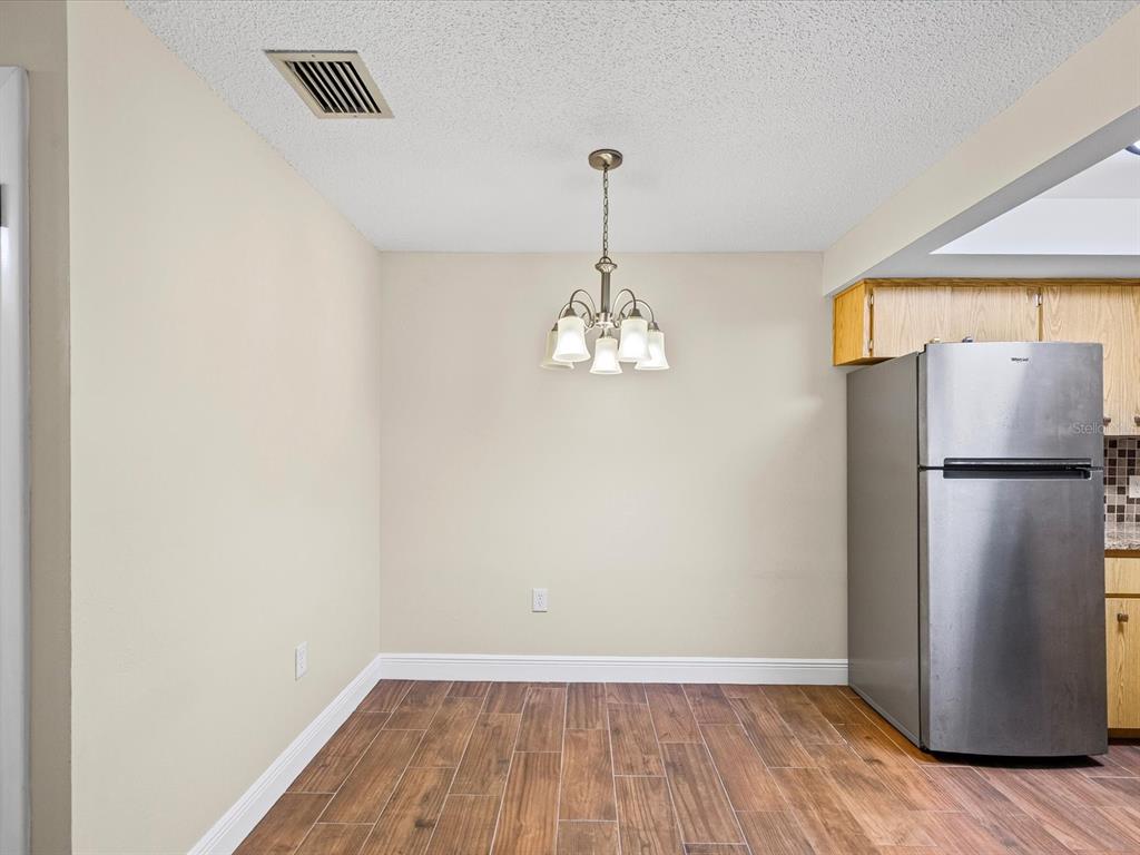 6037 Chesham Drive, Unit 7 New Port Richey, FL 34653 - Photo 13 of 29 a view of a room with wooden floor and a refrigerator