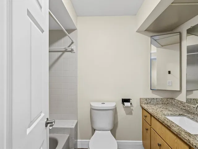 a bathroom with a granite countertop toilet and a sink