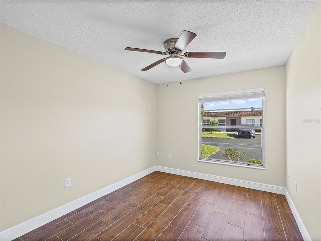 6037 Chesham Drive, Unit 7 New Port Richey, FL 34653 - Photo 18 of 29 a view of an empty room with a window and wooden floor