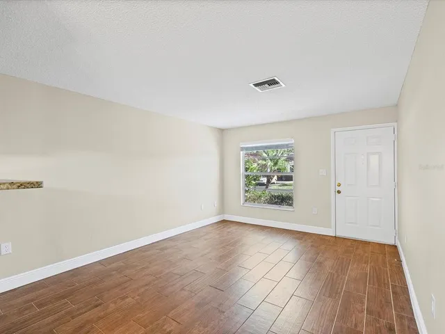 a view of an empty room with wooden floor and a window