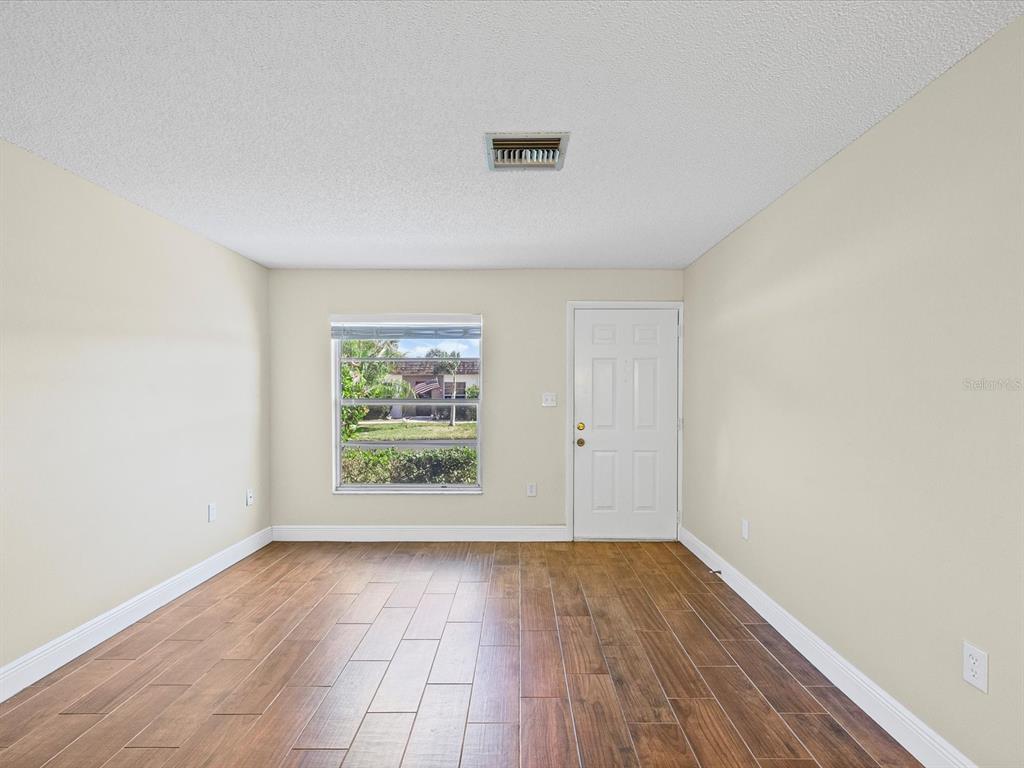 6037 Chesham Drive, Unit 7 New Port Richey, FL 34653 - Photo 8 of 29 an empty room with wooden floor and windows