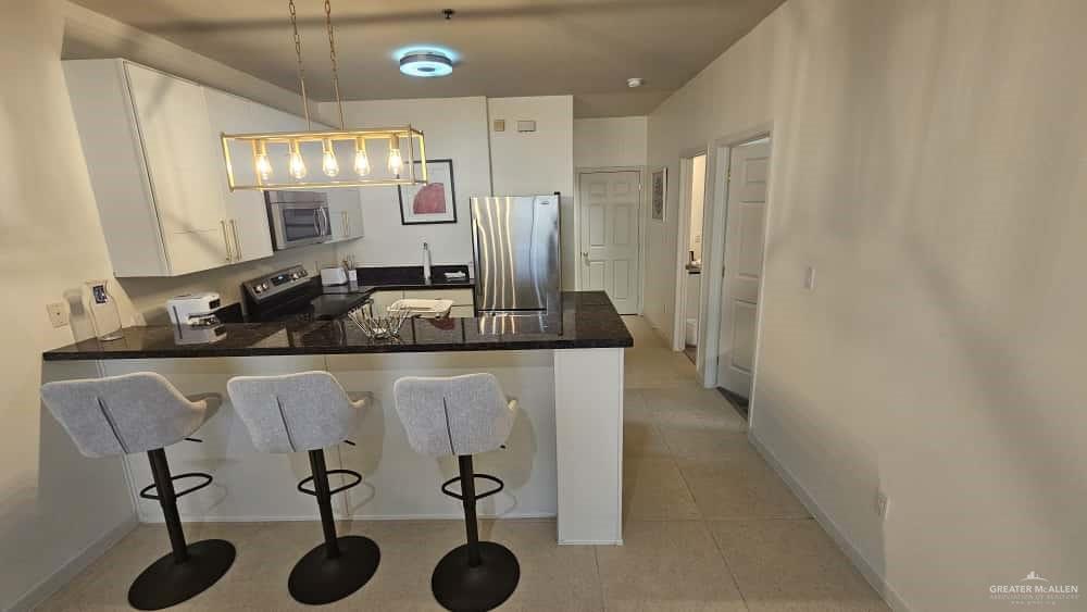 813 Travis Street, Unit 210 Mission, TX 78572 - Photo 2 of 13 a kitchen with a sink cabinets and chairs