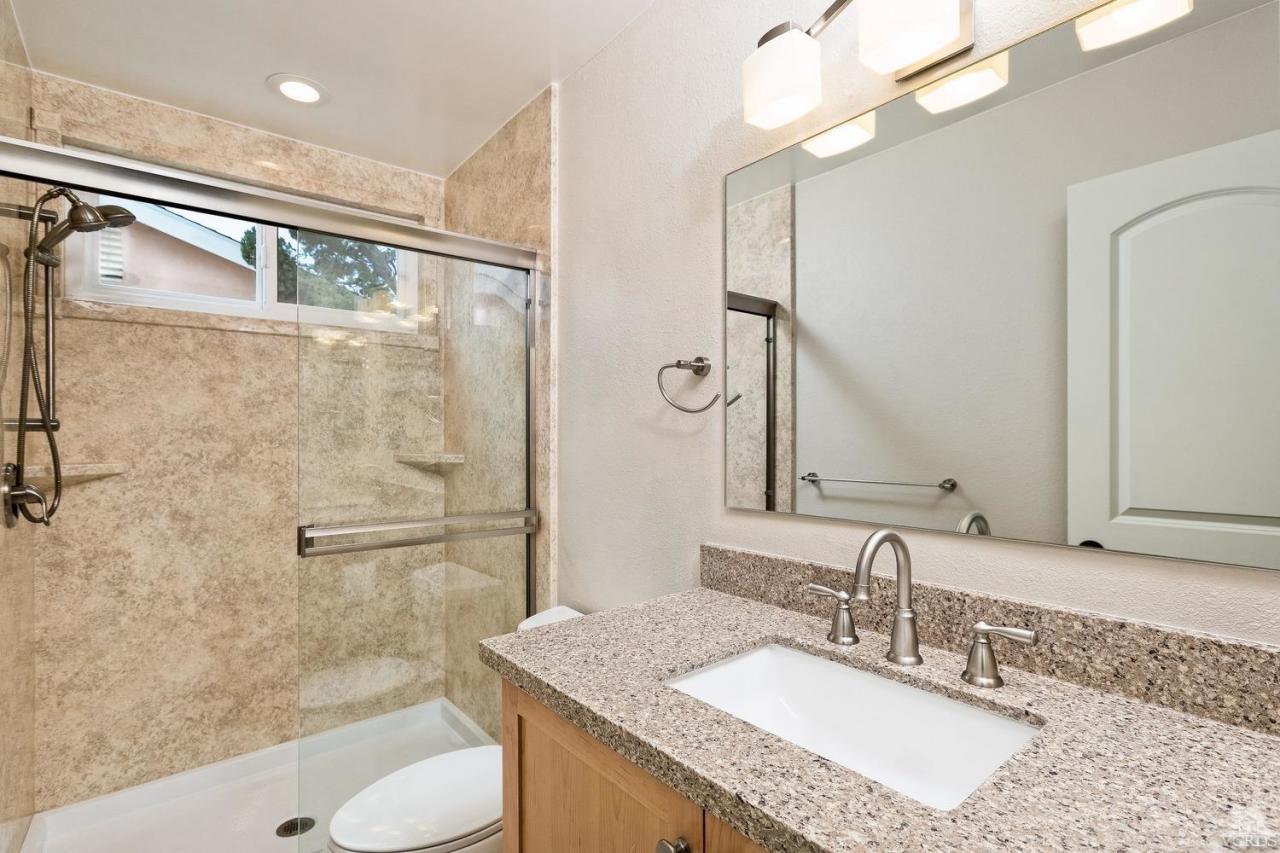 6449 Keystone Street Simi Valley, CA 93063 - Photo 12 of 20 a bathroom with a granite countertop sink a mirror a bathtub and shower