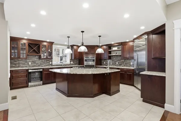 a large kitchen with granite countertop a large counter top and wooden cabinets