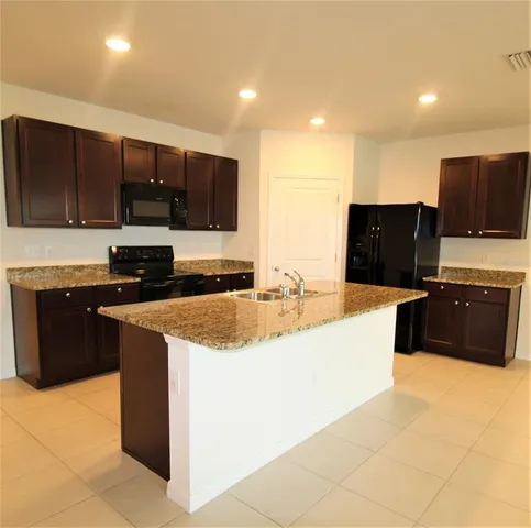 a large kitchen with stainless steel appliances a stove a sink and a microwave