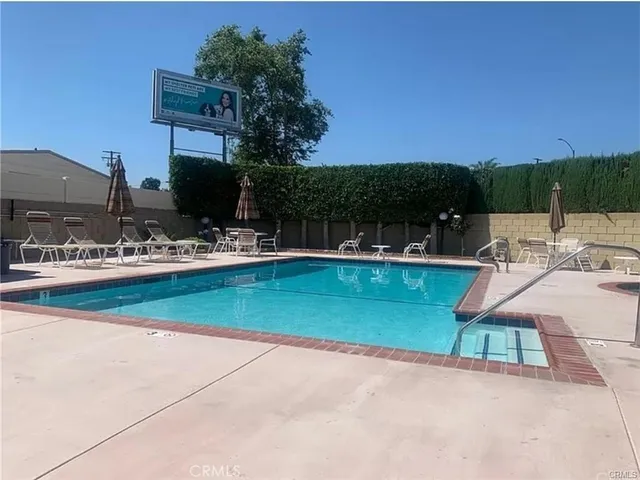 a view of a swimming pool with lawn chairs under an umbrella
