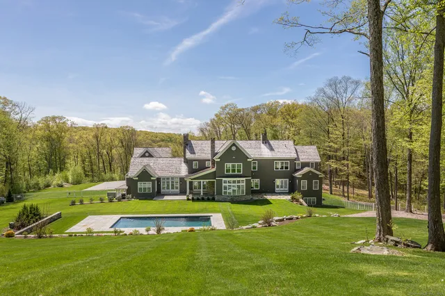 a view of a house with a big yard and large trees
