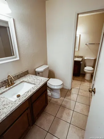 a bathroom with a granite countertop sink toilet and mirror