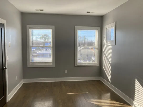 a view of an empty room with wooden floor and a window