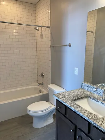 a bathroom with a granite countertop toilet a sink and bathtub