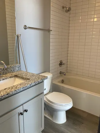 a bathroom with a granite countertop toilet a sink and bathtub