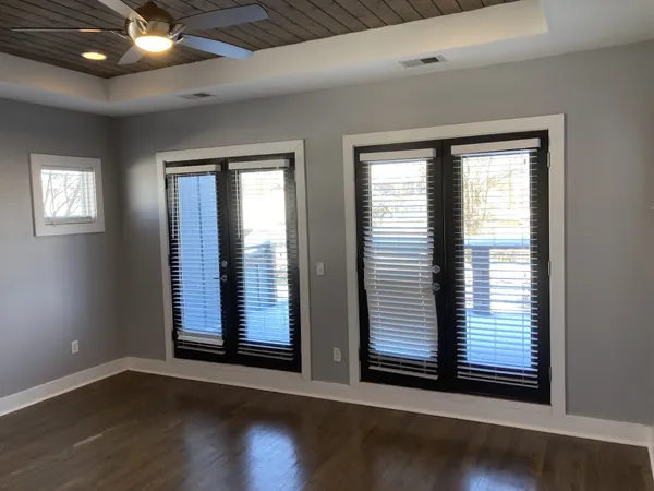 an empty room with wooden floor and windows