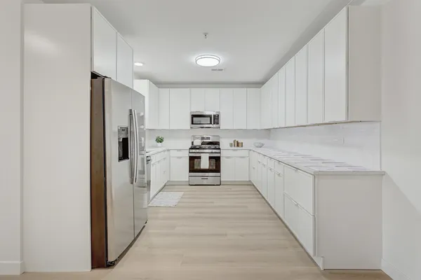 a kitchen with white cabinets and stainless steel appliances