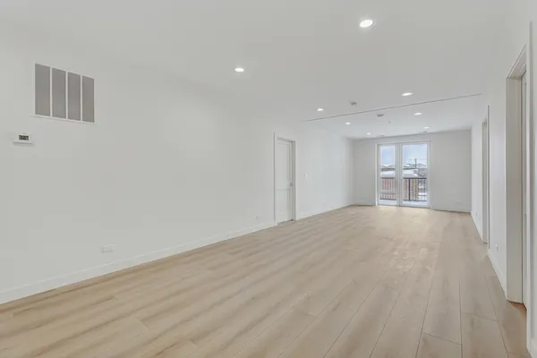 a view of empty room with kitchen and window