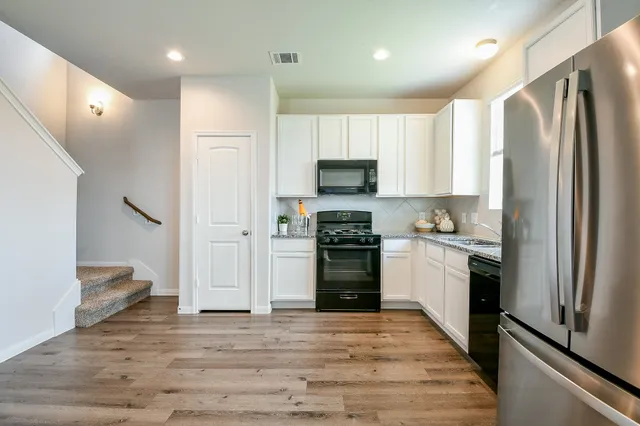 a kitchen with a refrigerator a sink and a stove top oven