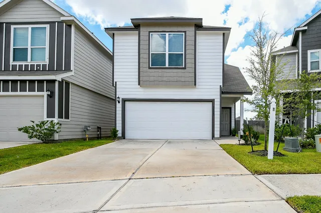a front view of a house with a garden and trees