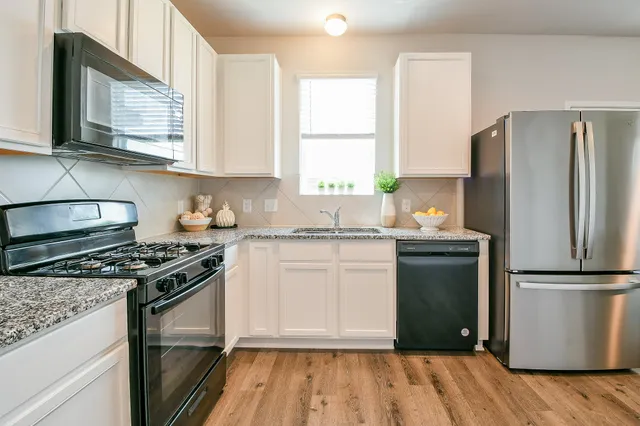 a kitchen with a refrigerator stove and wooden floor