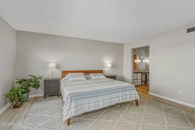 a bedroom with a bed table flowerpot and window