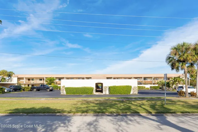 a view of a city street with a building and couple of cars parked in front of it
