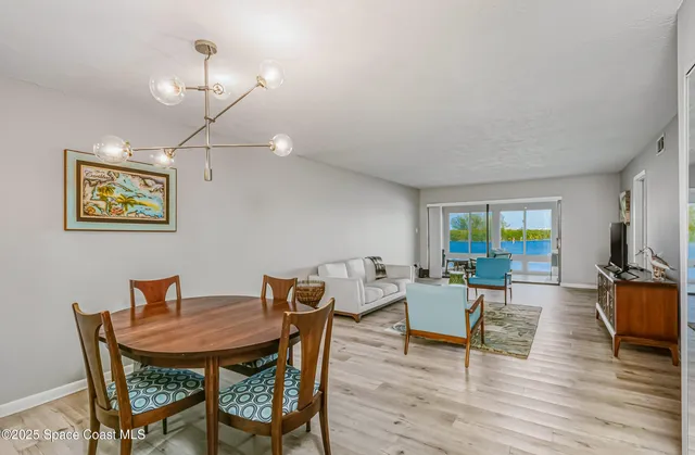 a view of a dining room with furniture a chandelier and wooden floor