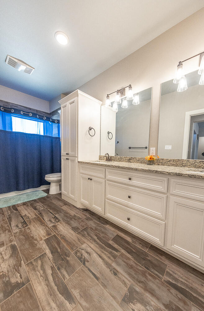 6961 103rd Street Lubbock, TX 79424 - Photo 16 of 32 a spacious bathroom with a granite countertop sink mirror and a toilet
