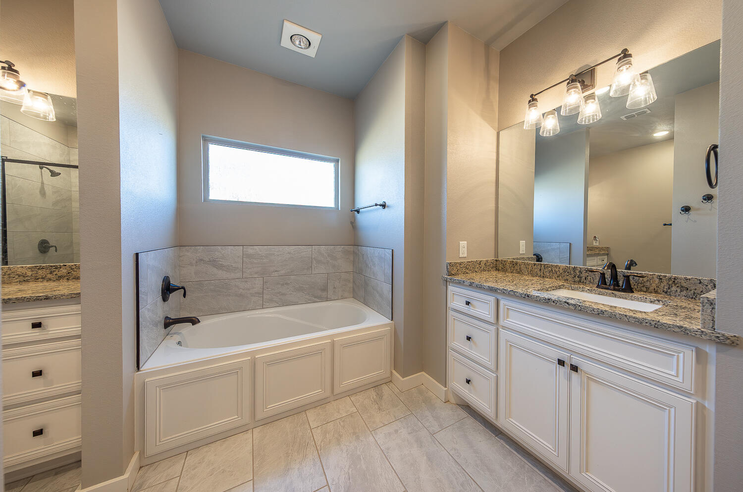 6961 103rd Street Lubbock, TX 79424 - Photo 21 of 32 a spacious bathroom with a granite countertop tub a double vanity sink and mirror