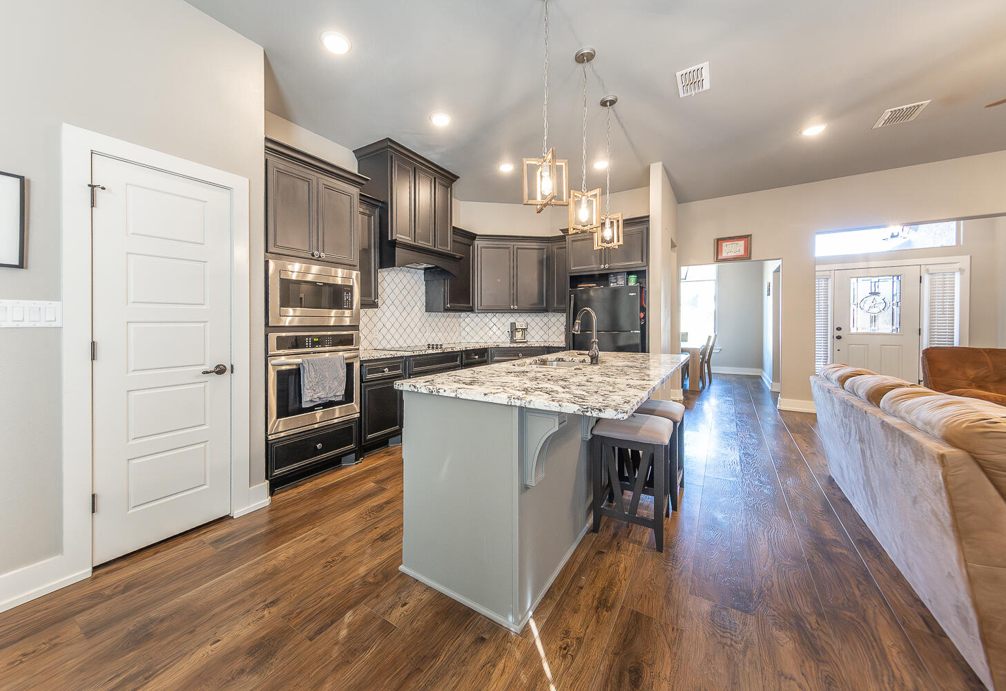 6961 103rd Street Lubbock, TX 79424 - Photo 8 of 32 a kitchen with stainless steel appliances kitchen island granite countertop a wooden floors and a view of living room