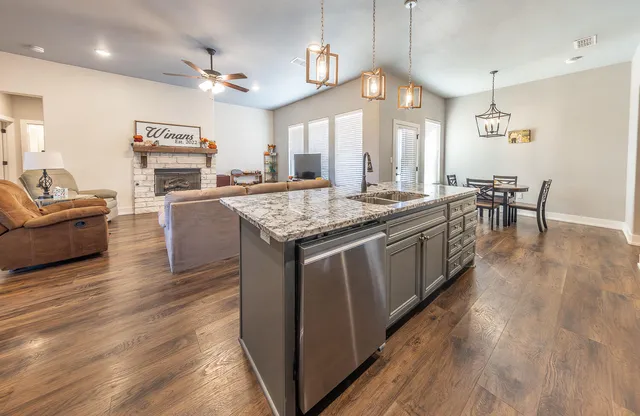 a kitchen with stainless steel appliances granite countertop wooden floors and white cabinets