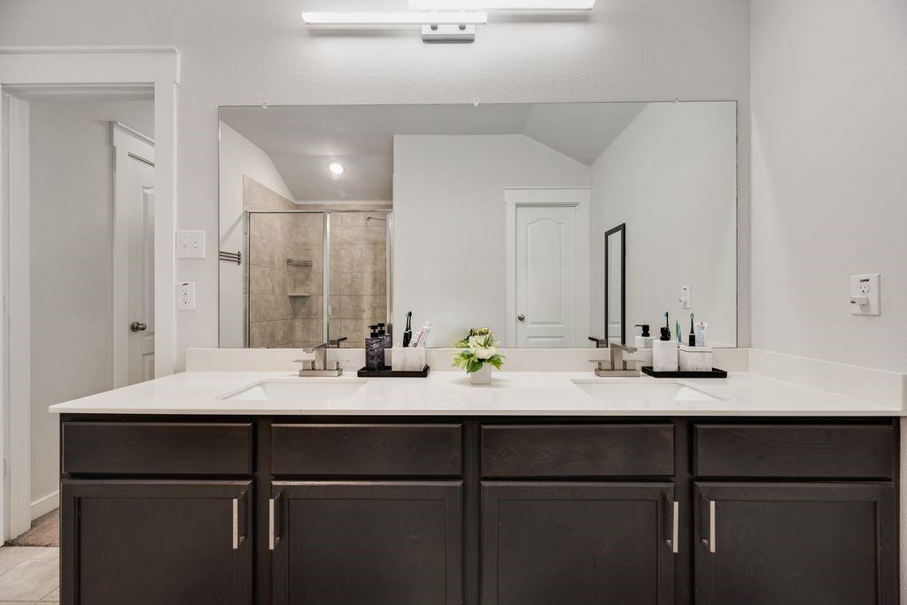 2702 Runnels Court Forney, TX 75126 - Photo 17 of 32 The bathroom features a double vanity with dark wood cabinetry, white countertops, and two rectangular sinks