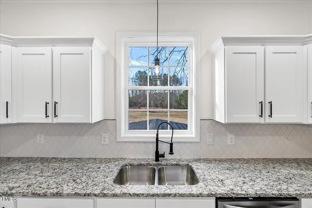 a kitchen with granite countertop a sink and white cabinets