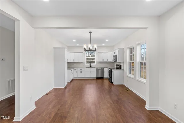 a large kitchen with cabinets wooden floor and stainless steel appliances