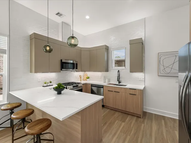 a kitchen with stainless steel appliances a stove a sink dishwasher a refrigerator and white cabinets with wooden floor