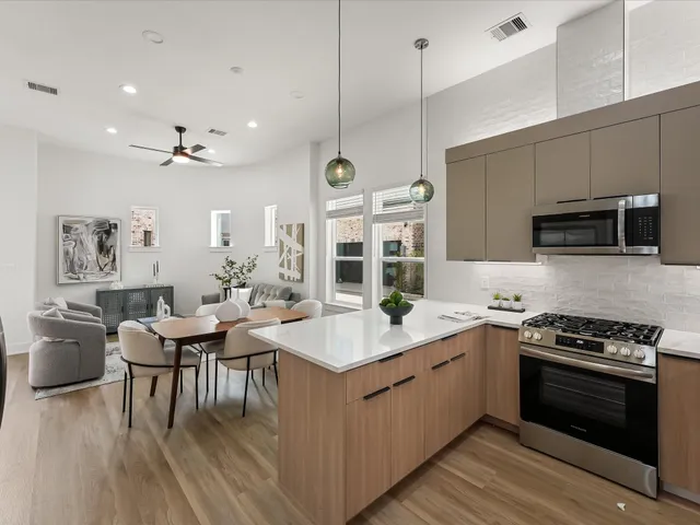 a kitchen with stainless steel appliances granite countertop a stove a sink dishwasher and a dining table with wooden floor