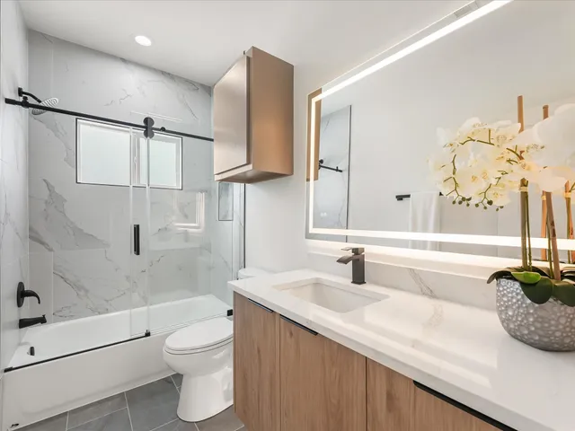a bathroom with a granite countertop sink a toilet and shower