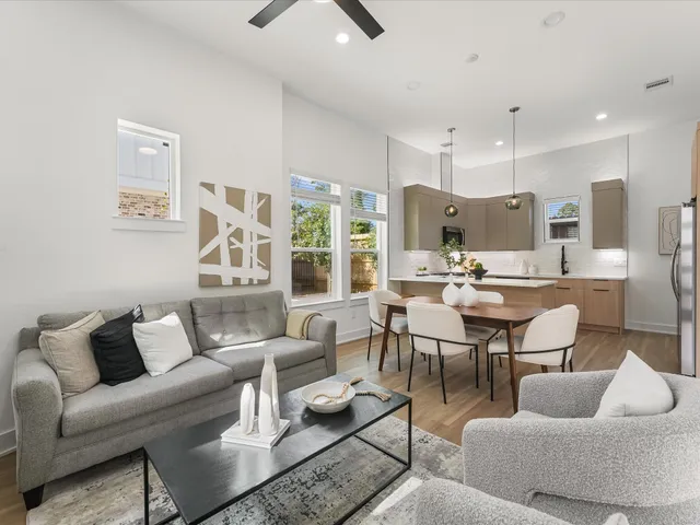 a living room with furniture kitchen view and a large window