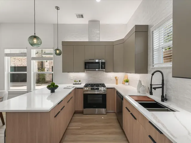 a large kitchen with stainless steel appliances granite countertop a sink a stove and a wooden floors