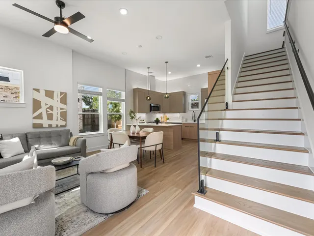 a living room with couches and kitchen view with wooden floor