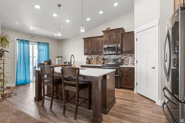 463 South Trejo Ridge Road Grantsville, UT 84029 - Photo 4 of 22 Contemporary kitchen featuring dark wood-finish cabinetry, stainless steel appliances, a center island with seating, and wood-finish flooring